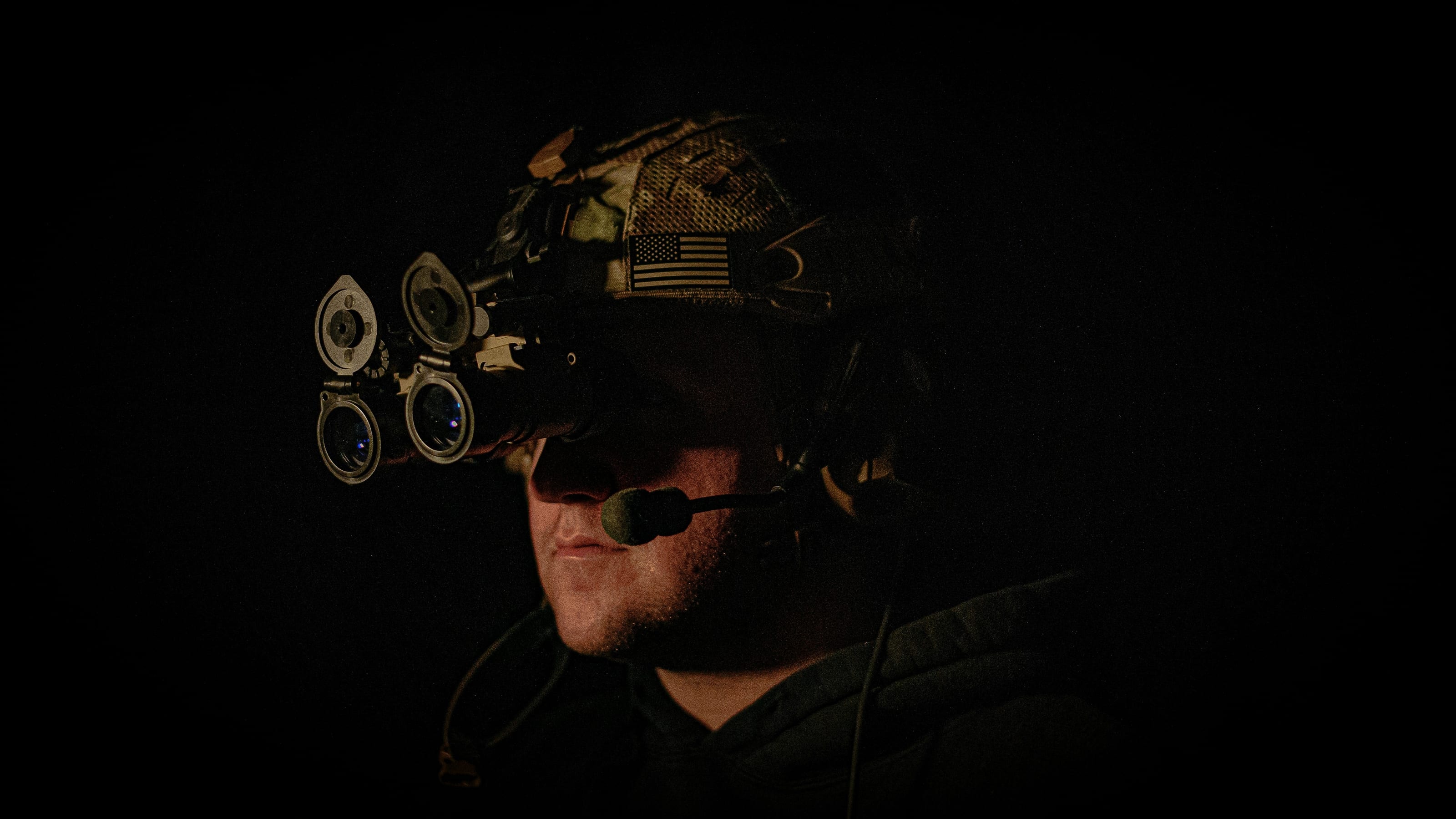 Operator wearing quad-tube night vision goggles in the dark
